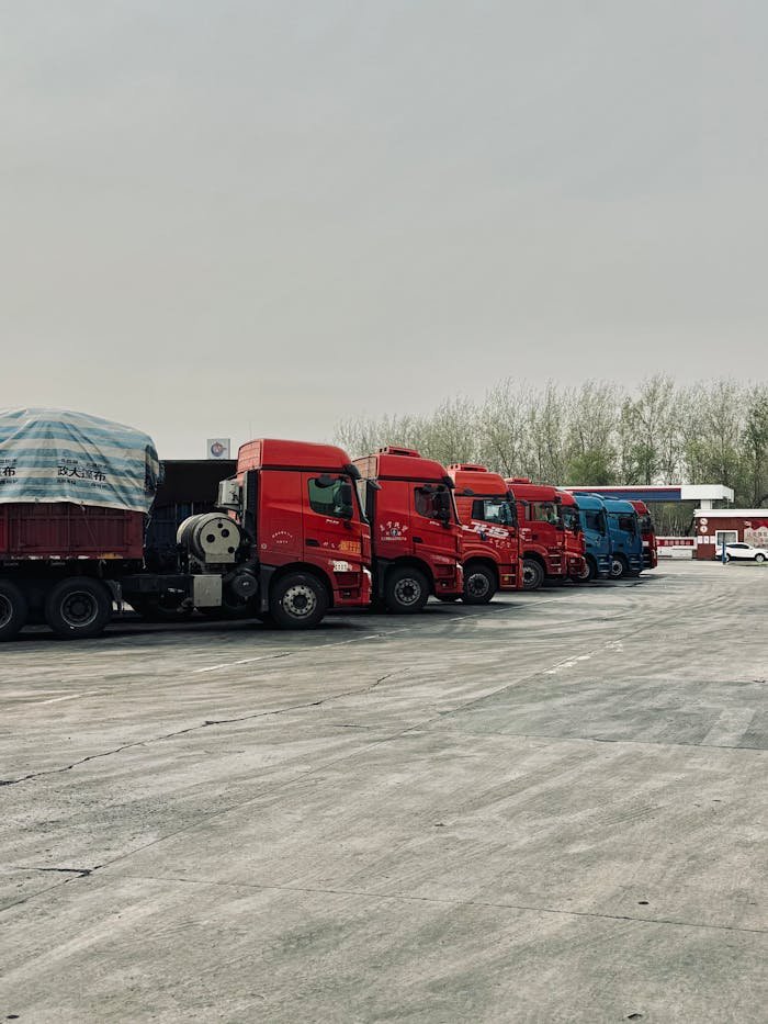 Line of red trucks parked outdoors in Tianjin, China, showcasing transportation logistics.